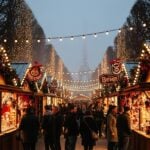 Tuileries Garden Christmas market in Paris with festive stalls and Eiffel Tower in background.