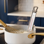 Low-glycemic syrup simmering in a saucepan with a candy thermometer in a modern kitchen.