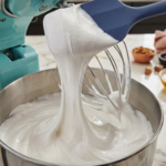 Glossy marshmallow mixture stretching from a spatula inside a mixing bowl.