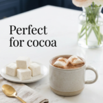 Mug of hot cocoa topped with sugar-free marshmallows on a kitchen counter.