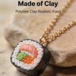 Mini sushi roll pendant made from polymer clay with realistic rice and salmon detail.