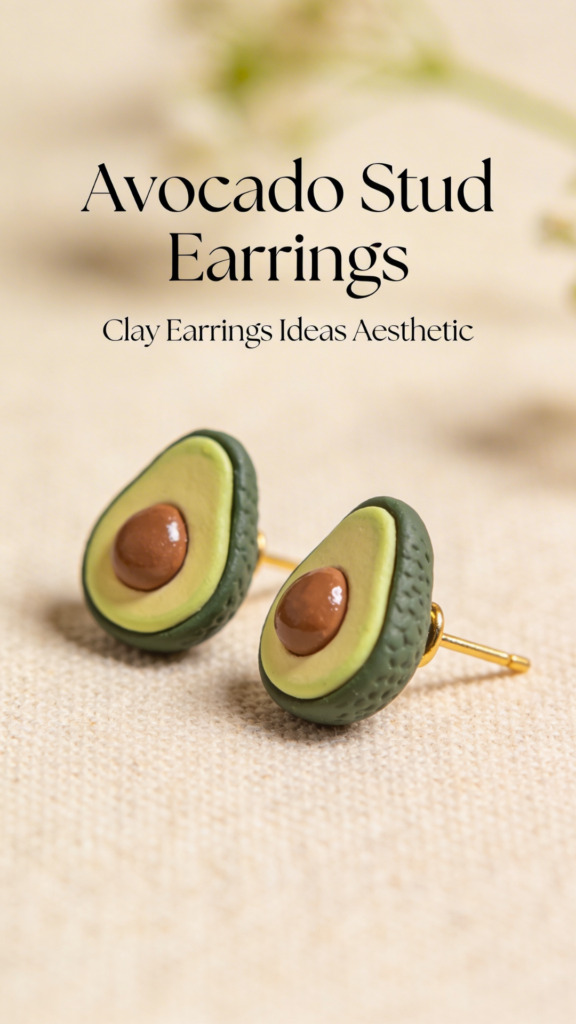 Realistic avocado stud earrings made from polymer clay with textured green skin and brown seed detail.