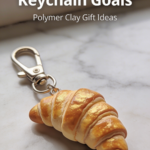 Mini croissant keychain made from polymer clay with golden flaky texture.