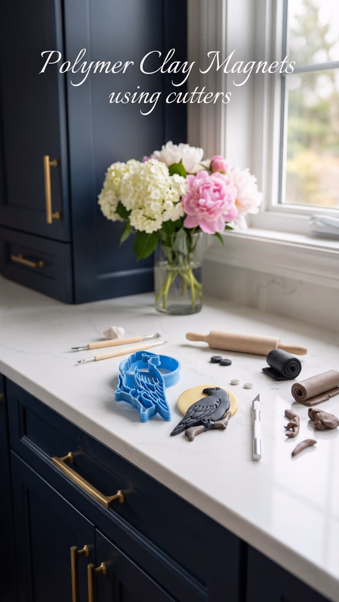 Polymer clay tools and a blue clay cutter next to a raven clay shape on a white countertop in a dark blue kitchen.
