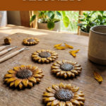 Handmade sunflower clay magnets on a wooden table near a window with clay tools, petals, and a ceramic mug.