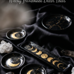 Black clay incense holders with gold moon phase details styled on black satin with crystals in a witchy celestial flat lay.