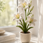 Crocheted white lily plant with tall green stems yellow stamens and matching crochet pot displayed on a marble windowsill with sheer curtains and soft morning sunlight