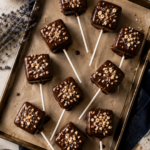 Tray of finished low carb chocolate covered marshmallow pops topped with hazelnuts, easy keto candy recipe