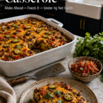 White ceramic baking dish filled with a golden baked keto Mexican breakfast casserole with chorizo, diced red peppers, jalapeño slices, scrambled eggs, and melted cheddar, with one slice removed onto a speckled plate in the foreground, styled on a white marble countertop with dark navy cabinetry and brushed gold hardware in the background.