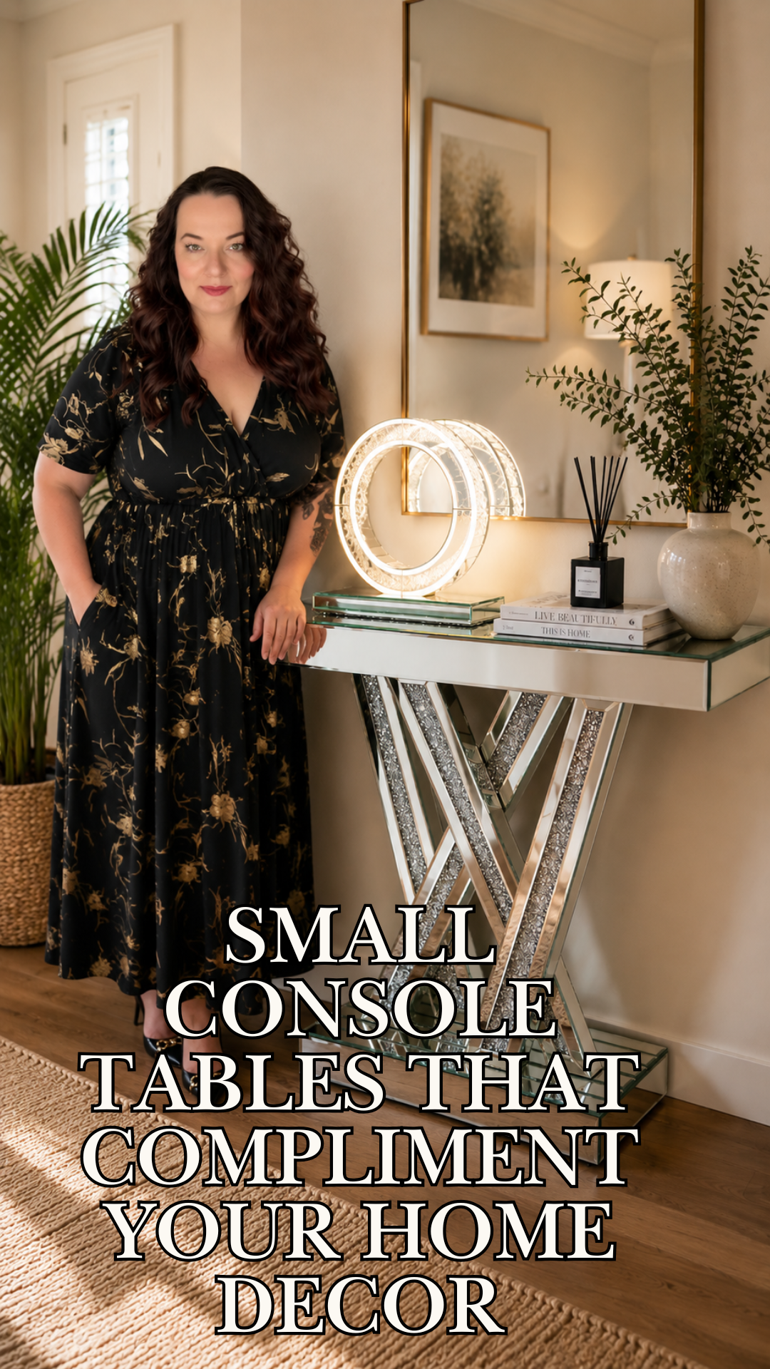 Close-up of a mirrored glass console table with sparkling crystal accent legs, topped with a round light fixture, books, a diffuser, and a textured white vase against a neutral wall.