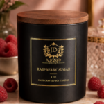 Luxury handcrafted soy candle in a matte black vessel with wooden lid and gold foil label reading Raspberry Sugar by Aligned Design, styled with fresh raspberries and a gold spoon on a marble surface.