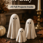 Three standing white air-dry clay ghost figurines with dot eyes on a dark wood surface with fall leaves, a lit taper candle, and a mini white pumpkin, pin titled "One Bag of Clay — 25 Fall Projects Inside"