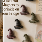 Six small handmade clay witch hat magnets with floppy droopy tips, painted in soft charcoal, dusty plum, and muted sage, arranged casually on a white fridge door beside a grocery list and a child's drawing pinned nearby.