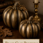 Three vintage brass-look air dry clay pumpkins on a Thanksgiving table setting with cream tapers and dried wheat
