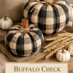 Two buffalo check painted air dry clay pumpkins with cinnamon stick stems on a rustic wood board with dried wheat and mini white pumpkins