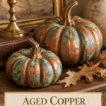 Two aged copper patina air dry clay pumpkins with teal and sage green finish on a dark walnut side table with a brass candlestick