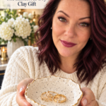 Woman holding a handmade speckled air dry clay trinket dish with a gold-painted rim and gold rings inside. Text overlay reads “Speckled Clay Trinket Dish – The Easiest Air Dry Clay Gift” with a “Save for Christmas Gifting” CTA.