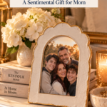 A cream scalloped arch air dry clay photo frame with a gold edge, holding a family photo of a woman, a man, and two young men, on a white dresser with hydrangeas, books, and a candle. The text reads "DIY Clay Arch Photo Frame, A Sentimental Gift for Mom" and "Save for Christmas."