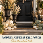 Modern neutral fall front porch with matte black door, eucalyptus wreath tied with a cream velvet bow, tall matte black classical fluted urns overflowing with dried pampas grass and eucalyptus, cream heirloom pumpkins and white mini pumpkins clustered on the steps, sage green pumpkins with matte black ceramic vases on the right, layered natural coir and black striped doormats, white mums, warm golden hour light.