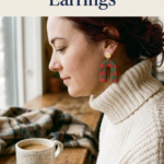: Woman in a cream turtleneck sweater wearing a red and green buffalo check polymer clay arch earring with a gold stud, sitting by a window with a mug of coffee.
