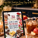 A tablet showing the cover of a 31 low carb no-bake dessert recipes ebook with keto cheesecake jars, berry parfaits, lemon bars and truffles, on a marble counter beside a mug of hot apple cider topped with marshmallows, a plate of apple cider marshmallows, red apples and cinnamon sticks.